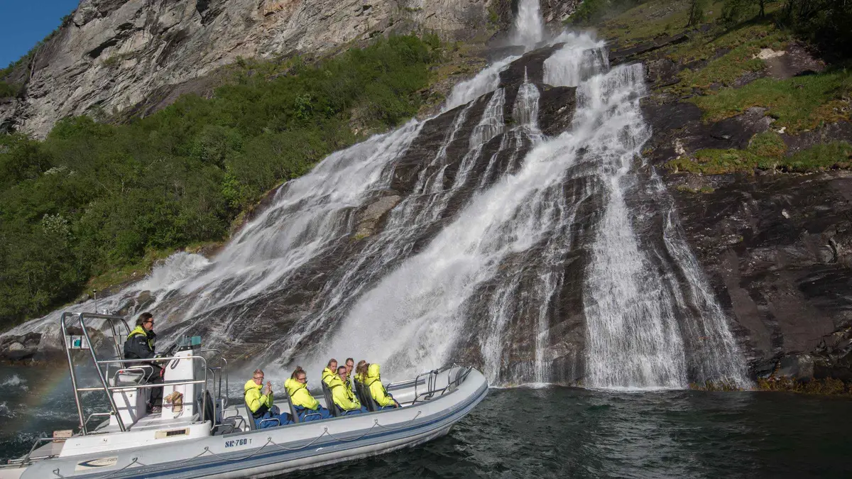 Open RIB boat speeding toward the Seven Sisters waterfall on a Geiranger fjord cruise safari in Norway