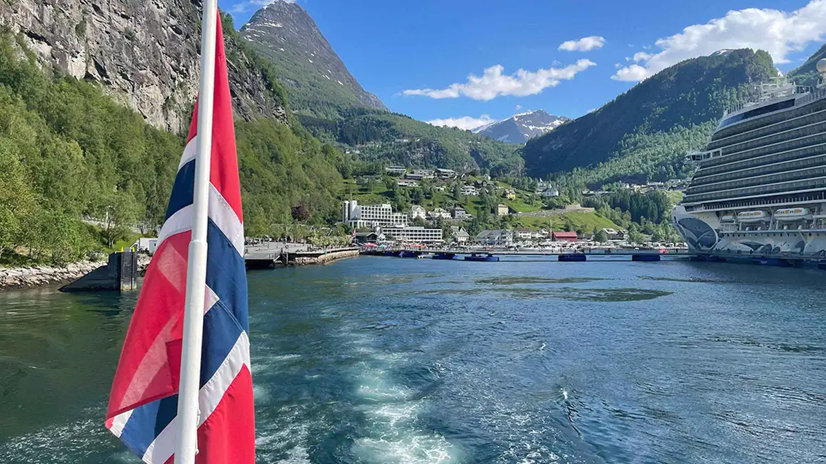 Catamaran on a Geiranger fjord cruise approaching Hellesylt village at the mouth of the fjord in Norway